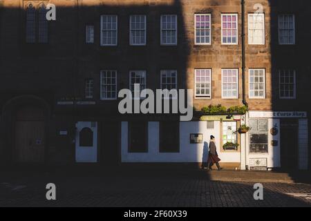 Edinburgh, Schottland - Januar 19 2020: Moody, dramatische Licht- und Schattenstraßenszene einer Frau, die entlang der historischen Altstadt Royal Mile in Edin geht Stockfoto