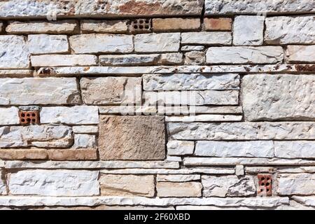 Marmorwand, aus mehreren Marmorstücken, die einen interessanten Texturhintergrund schaffen, in Filopappos Hill, Athen, Griechenland. Stockfoto