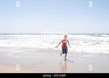 Junge am Meer, der vor den Wellen läuft Stockfoto