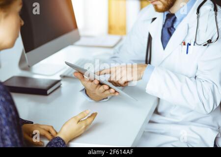 Freundliche männliche Arzt und geduldige Frau diskutieren aktuelle Gesundheitsuntersuchung Während der Sitzung in der sonnigen Klinik Stockfoto