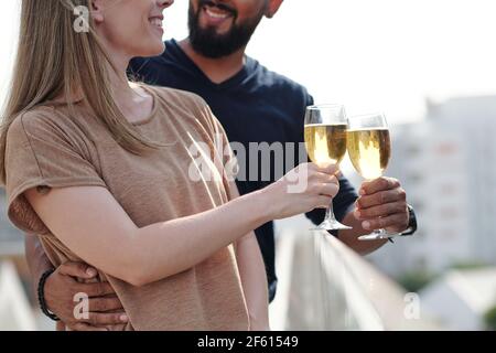 Zugeschnittenes Bild von lächelndem umarmenden jungen Paar genießen Champagner trinken Auf dem Dach Stockfoto