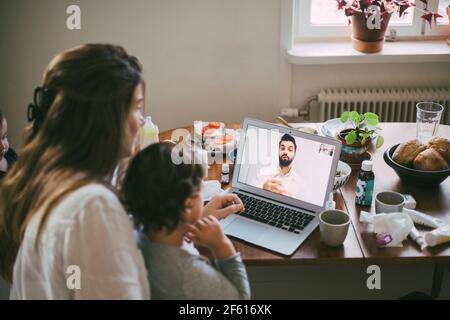 Mutter mit kranken Sohn, der Rat von einem männlichen Arzt einnahm Videoanruf im Wohnzimmer Stockfoto