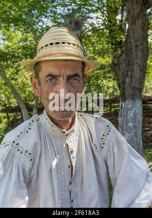 Salaj, Transsilvanien, Rumänien-14. Mai 2018: Portrait eines rumänischen Bauern mit blauen Augen in einem traditionellen Volkstrikot und einem Hut am Sommertag Stockfoto