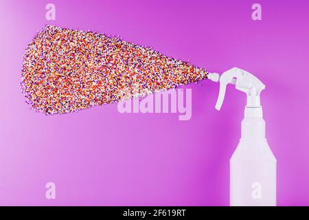 Sprühen Sie Spritzer mit farbigen Kugeln auf einem rosa Hintergrund. Freiraum-Konzept Stockfoto