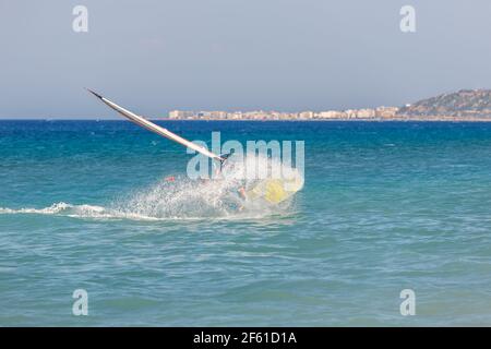 Windsurfen macht extreme Stunts auf dem Wasser, fällt ins Meer, viele Spritzer Stockfoto