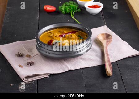 Huhn mit rohem Bananencurry (Kochbananen), würziges Huhn mit grüner Banane Schmackhaferes indisches Gericht in einem Geschirr, das auf ist angeordnet Ein Gewebe mit schwarzem b Stockfoto