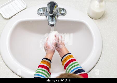 Kleines Kind, das im Badezimmer Hände mit Seife wascht Stockfoto
