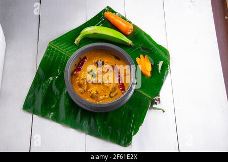 Huhn mit rohem Bananencurry (Kochbananen), würziges Huhn mit grüner Banane Schmackhaferes indisches Gericht in einem Geschirr, das auf ist angeordnet Bananenblatt mit Whi Stockfoto