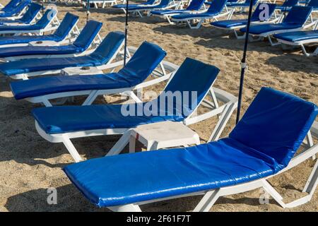Reihe von blauen Sonnenliegen am Sandstrand Stockfoto