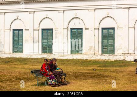 Murshidabad, Westbengalen, Indien - Januar 2018: Eine indische Familie sitzt auf einer Bank außerhalb des alten Nizamat Imambara in der Stadt Murshidabad. Stockfoto