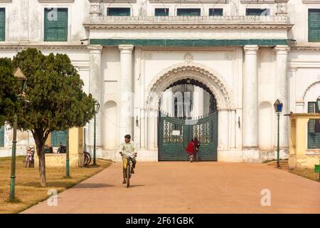 Murshidabad, Westbengalen, Indien - Januar 2018: Ein Mann auf dem Fahrrad auf der Straße, die zum alten Tor des Nizamat Imambara in Murshid führt Stockfoto