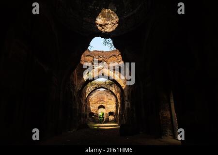 Die überwucherten Ruinen einer alten Festung mit eleganten Bögen in der Stadt Murshidabad in Westbengalen, Indien. Stockfoto