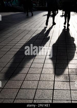 Silhouette von unerkannten Menschen, die auf der Straße spazieren. Stockfoto