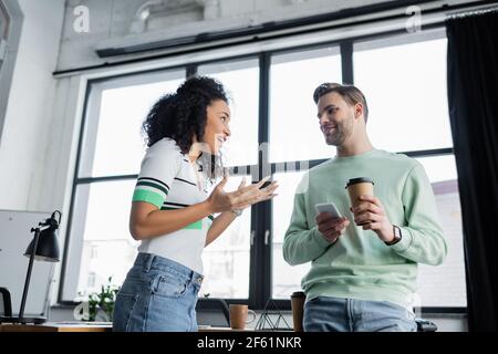 Aufgeregt afroamerikanische Geschäftsfrau gesturing, während im Gespräch mit lächelnden Kollegen Stockfoto