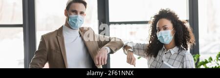 Multikulturelle Geschäftsleute in medizinischen Masken tun Ellenbogen Beule im Büro, Banner Stockfoto