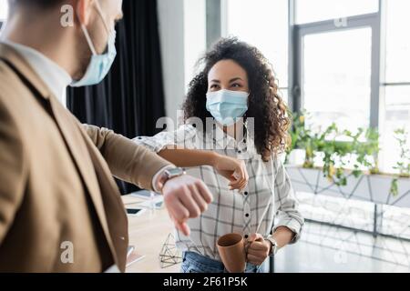 afroamerikanische Geschäftsfrau tun Ellenbogen Beule mit Kollegen auf verschwommen Vordergrund Stockfoto