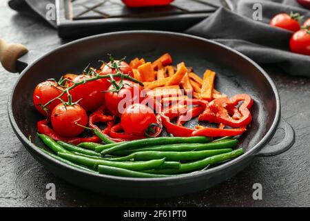 Bratpfanne mit leckerem Gemüse auf dunklem Hintergrund Stockfoto