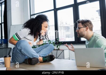 Wütend interracial Geschäftsleute streiten in der Nähe von Kaffee zu gehen und Notebook Stockfoto