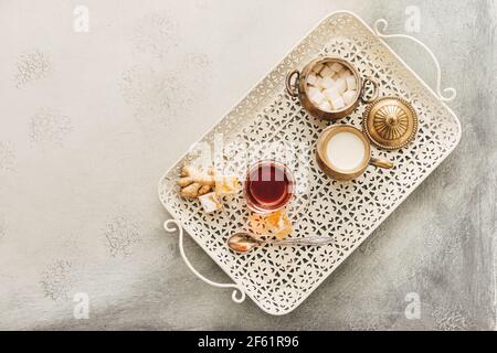 Ein Glas leckeren türkischen Tee und Köstlichkeiten auf hellem Hintergrund Stockfoto