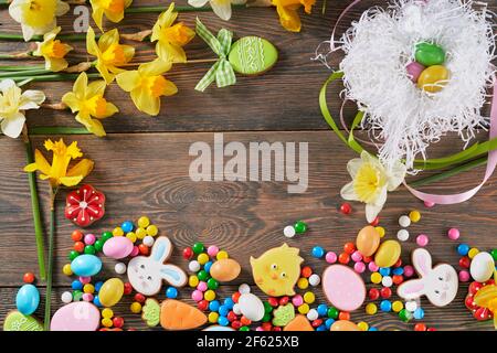 Draufsicht Porträt mit Platz für Text von osterkeksen, Süßigkeiten und Blumen auf Holzhintergrund. Hausgemachter Lebkuchen in unterschiedlicher Form und Größe. Stockfoto