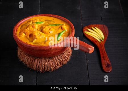 Garnelen Mango Curry, kerala traditionelle Gericht mit roher Mango und Angeordnet in einer irdenen Ware mit schwarzem texturierten Hintergrund Stockfoto