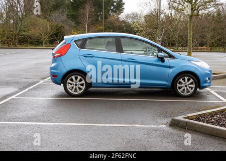 Hampshire, England, Großbritannien. 2021. Kleine blaue Limousine auf einem Parkplatz an einem nassen Tag. Stockfoto