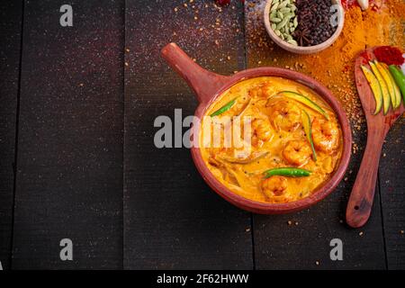 Garnelen Mango Curry, kerala traditionelle Gericht mit roher Mango und Angeordnet in einer irdenen Ware mit schwarzem texturierten Hintergrund Stockfoto