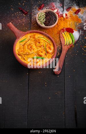 Garnelen Mango Curry, kerala traditionelle Gericht mit roher Mango und Angeordnet in einer irdenen Ware mit schwarzem texturierten Hintergrund Stockfoto