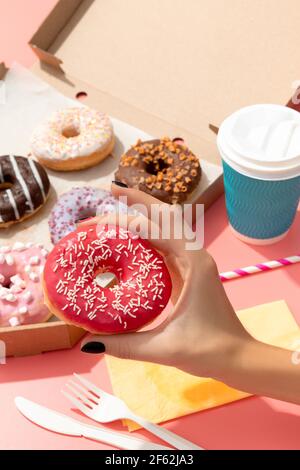 Set von leckeren bunten Donuts in Papier-Box auf rosa Hintergrund. Online-Lieferung Essen zum Mitnehmen Stockfoto