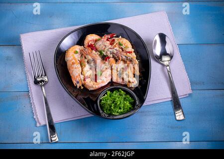 Butter Knoblauchgarnelen oder cremige Knoblauch Garnelen, die leckere asiatische Gericht in einem schwarzen Geschirr mit gehackten parsely als Salat angeordnet ist. Stockfoto