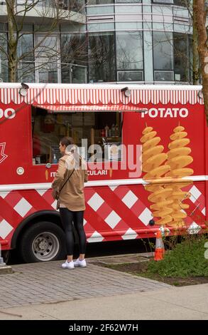 Frau, die Lebensmittel von einem Food Truck bestellt, der Spiralkartoffeln verkauft, Vancouver, British Columbia, Kanada Stockfoto