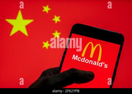 In dieser Abbildung zeigt das Logo der amerikanischen Fast-Food-Hamburger-Restaurantkette McDonald's auf einem Android-Mobilgerät mit der Flagge der Volksrepublik China im Hintergrund. Stockfoto