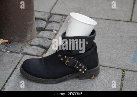 Schwarzer Schuh auf der Straße mit Einwegbecher Stockfoto