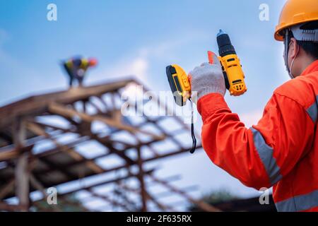 Dachwerkzeuge, Dachdecker Arbeiter halten elektrische Bohrmaschine auf neuen Dächern mit Metallblech auf der Baustelle verwendet. Stockfoto