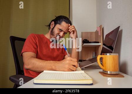 Junger Mann, der zu Hause arbeitet und studiert. Mann im Home Office. Stockfoto