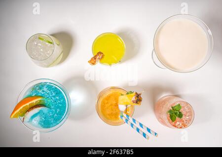 Farbenfrohe Getränke im Sommer. Verschiedene helle Alkoholcocktails und Getränke, in verschiedenen Gläsern, mit tropischen Früchten auf weißem Hintergrund Kopierraum Stockfoto