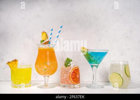 Farbenfrohe Getränke im Sommer. Verschiedene helle Alkoholcocktails und Getränke, in verschiedenen Gläsern, mit tropischen Früchten auf weißem Hintergrund Kopierraum Stockfoto