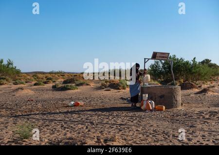 Erg Chebbi, Marokko - 12. April 2016: Eine Berberfrau sammelt Wasser aus einem Brunnen in Erg Chebbi, Marokko. Stockfoto