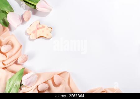 Lebkuchen in Form von Hasen mit rosa Eiern Auf pastellfarbenem Stoff und hellem Hintergrund Stockfoto