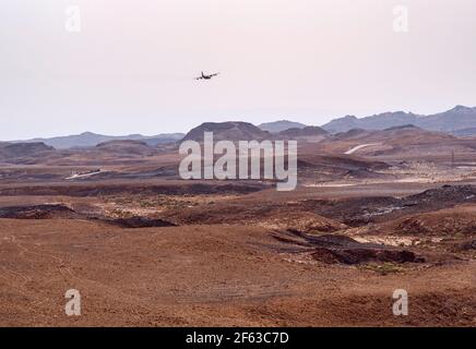 Detail der geologischen Phänomene des Bodens der Makhesh Ramon Krater in Israel mit einem militärischen Frachtflugzeug Tief im Hintergrund fliegen Stockfoto