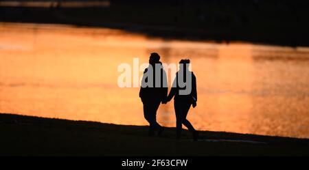 Dresden, Deutschland. März 2021, 29th. Zwei Menschen schilhouettierten am Ufer der Elbe bei Sonnenuntergang. Quelle: Sebastian Kahnert/dpa-Zentralbild/dpa/Alamy Live News Stockfoto