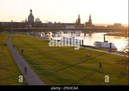 Dresden, Deutschland. März 2021, 29th. Die Menschen verbringen ihre Zeit bei Sonnenuntergang am Ufer der Elbe vor dem Hintergrund der Altstadt. Quelle: Sebastian Kahnert/dpa-Zentralbild/dpa/Alamy Live News Stockfoto