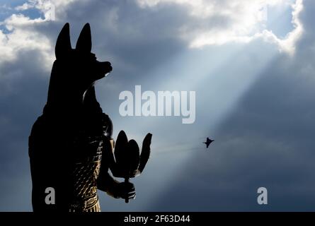 Stillleben von Statuen der Mythologie Schakal anubis inpu anup. Im Hintergrund ist ein blauer Himmel mit weißen und grauen Wolken und Überschallebene. Stockfoto