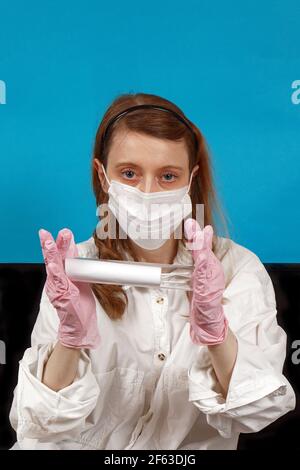 Junge Krankenschwester trägt Schutzmaske und Handschuhe halten Test Röhre im Krankenhaus Stockfoto