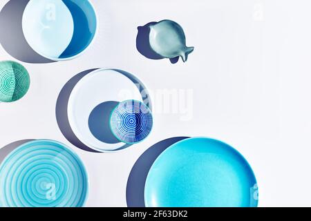 Blaue Keramikschalen und Teller auf weißem Hintergrund Draufsicht. Farbenfrohe Keramik leere Gerichte mit harten Schatten. Stockfoto