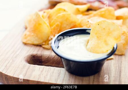 Kartoffelchips und Bad auf Holzbrett. Stockfoto