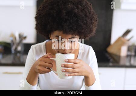 afroamerikanische Frau, die in der Küche sitzt und Kaffee trinkt Stockfoto
