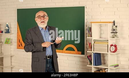 Niveau der Mathematik. Senior man Lehrer verwenden Werkzeug an der Tafel. Bärtige Tutor in Brille. Zurück zur Schule. Winkelmesser Lineal. Lernen Geometrie leicht. Werden Stockfoto