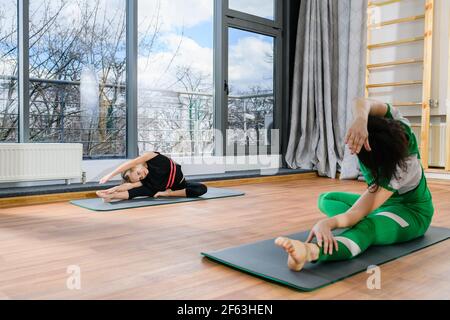 Frau und Tween Mädchen Übung Training, Yoga zusammen auf Sportmatte trainieren, machen Seitenhänge in hellen Halle Stockfoto