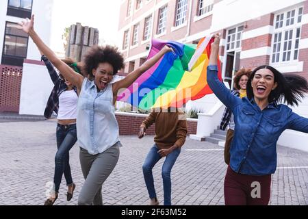 Verschiedene männliche und weibliche Demonstranten hielten am märz Regenbogenfahne in der Hand und jubelten mit erhobenen Waffen Stockfoto